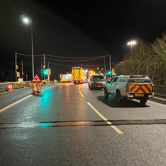 A truck drives along a road illuminated by streetlights at night.